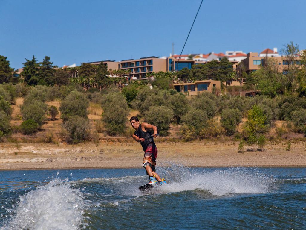 Ap Lago Montargil - Conference & Spa Luaran gambar The photo shows a person wakeboarding on a body of water. The individual is being pulled by a cable, which is likely connected to a boat or a winch. The person is wearing a life jacket and swim shorts, balancing on the board as they enjoy the activit