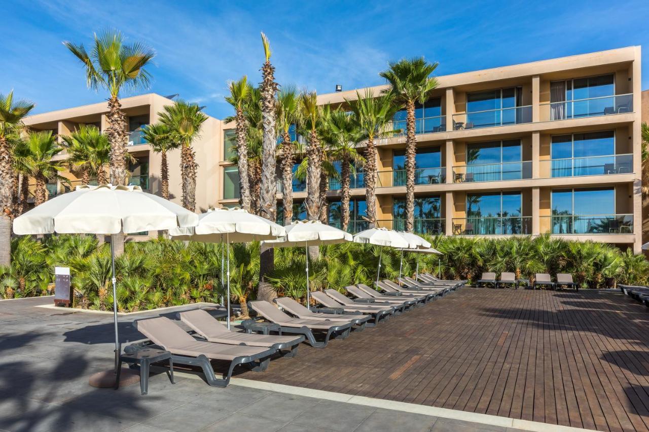 Ap Lago Montargil - Conference & Spa Luaran gambar The photo shows a modern resort or hotel area featuring several lounge chairs lined up on a wooden deck. Each lounge chair is paired with a white umbrella, providing shade. In the background, there are palm trees, which add to the tropical atmosphere