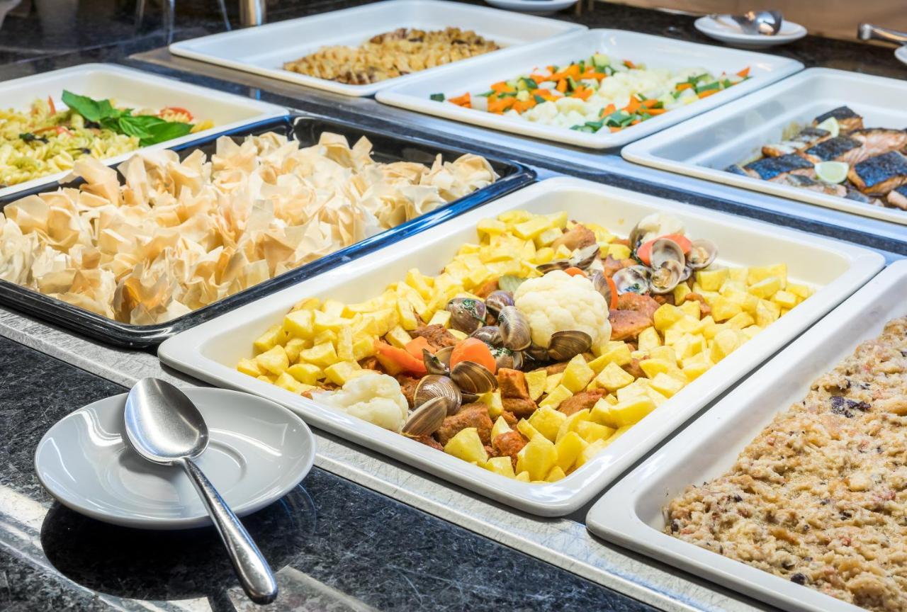 Ap Lago Montargil - Conference & Spa Luaran gambar The photo shows a buffet-style display of various dishes. There are several rectangular trays filled with different types of food. 

1. One tray contains a mix of vegetables and seafood, likely including potatoes and cauliflower.
2. Another tray hold