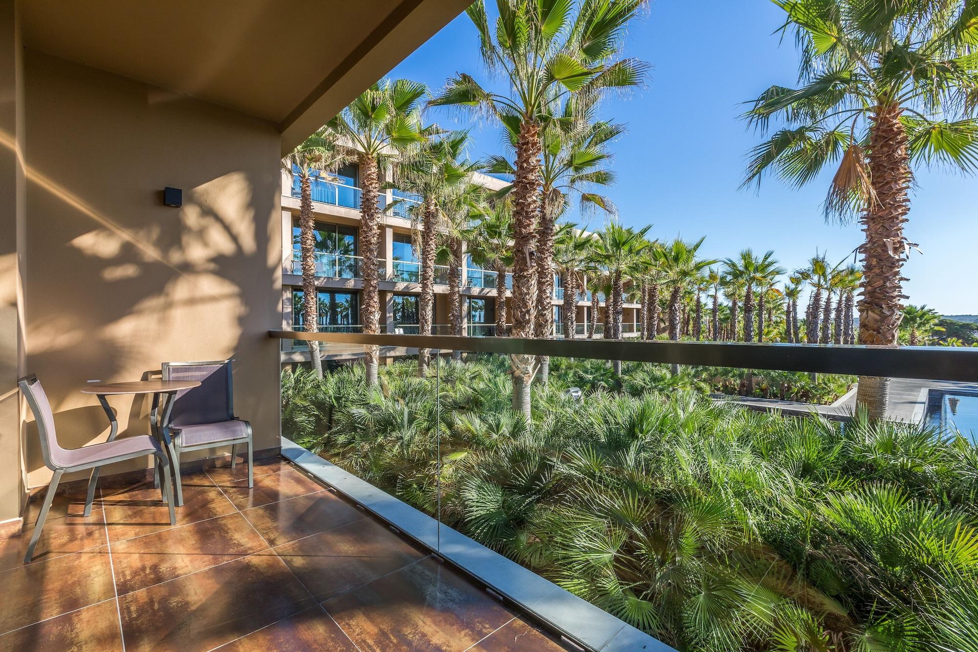Ap Lago Montargil - Conference & Spa Luaran gambar The photo shows a balcony with modern furniture, including a chair and a small table. In the background, there are tall palm trees and lush greenery, suggesting a tropical or resort-like setting. The buildings in the distance are likely part of a hot