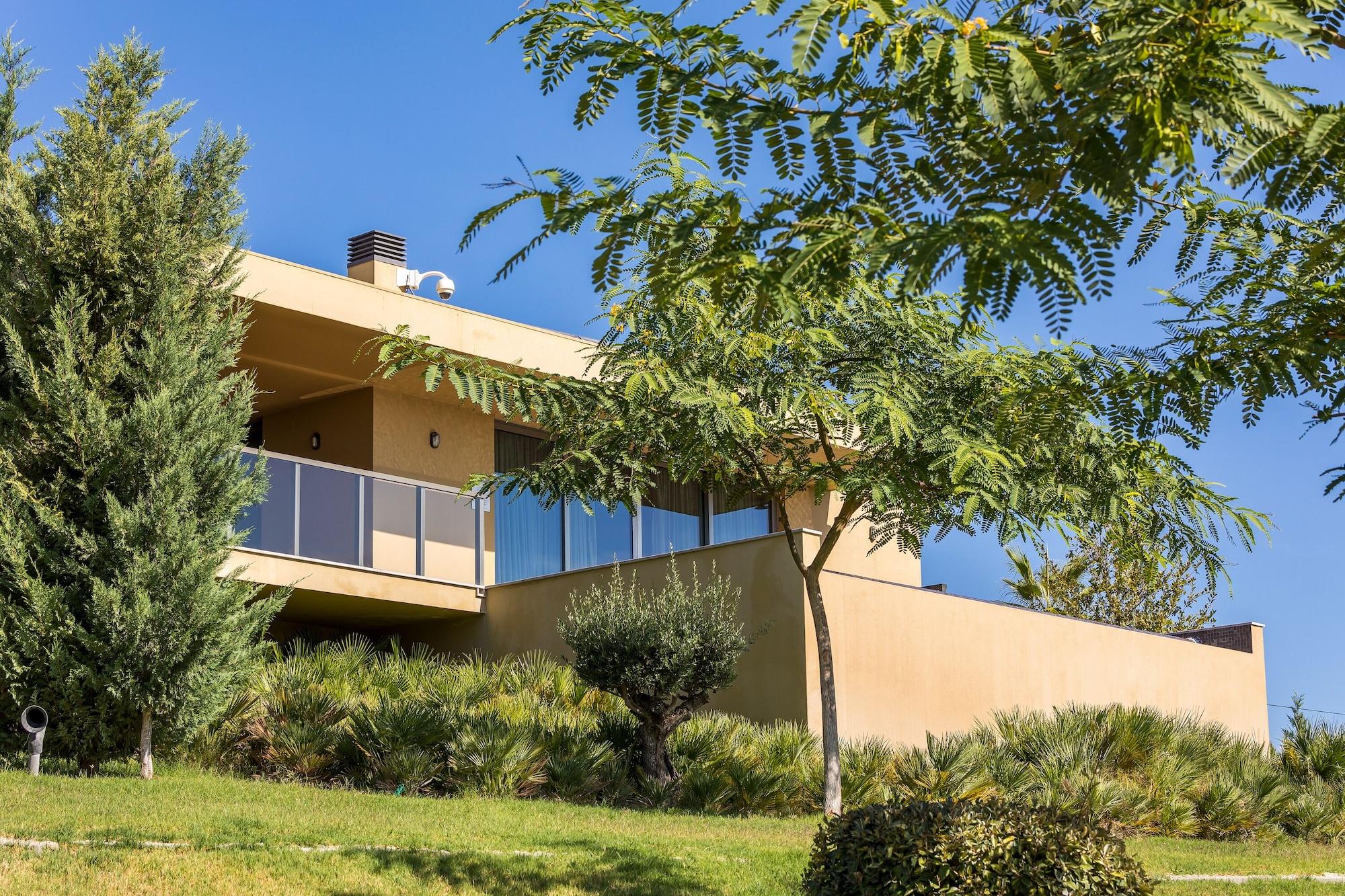 Ap Lago Montargil - Conference & Spa Luaran gambar The photo showcases a modern house situated on a grassy slope. The house features a light-colored exterior with large windows and a balcony. Surrounding the building are several trees and landscaping that enhances the natural environment. The sky is 