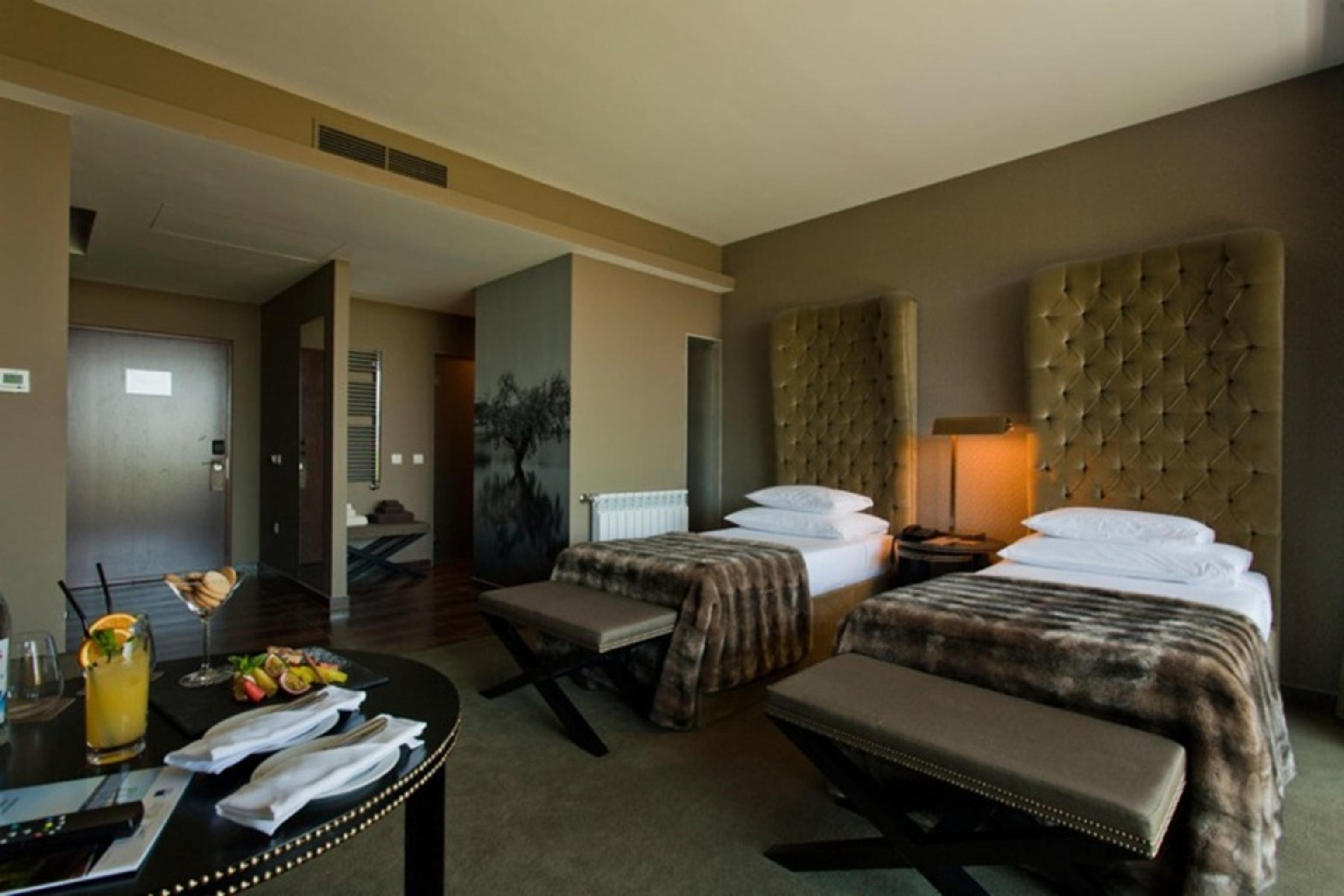 Ap Lago Montargil - Conference & Spa Luaran gambar The photo shows a stylish hotel room featuring two beds with plush, upholstered headboards. The room has a modern and elegant design, with earthy tones dominating the decor. A small round table is set up in the foreground, displaying a drink and some